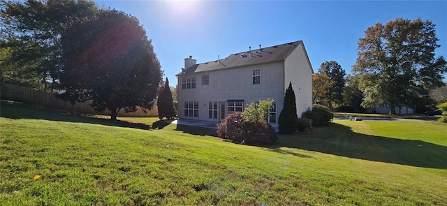 rear view of property with a yard, a chimney, and a patio area