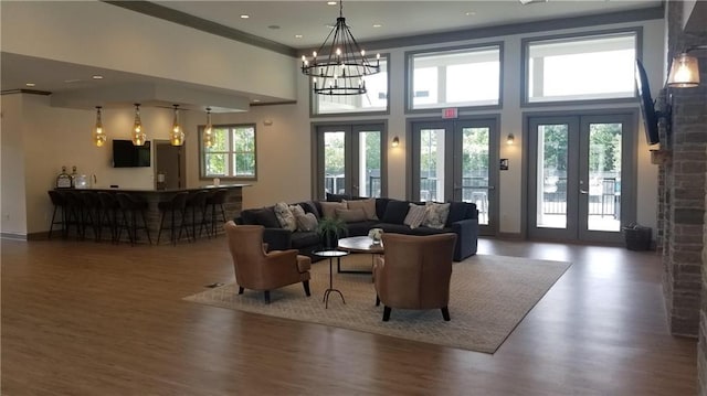 living room featuring french doors, a towering ceiling, baseboards, and wood finished floors