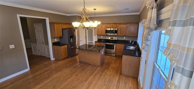 kitchen featuring a chandelier, stainless steel appliances, wood finished floors, a kitchen island, and ornamental molding