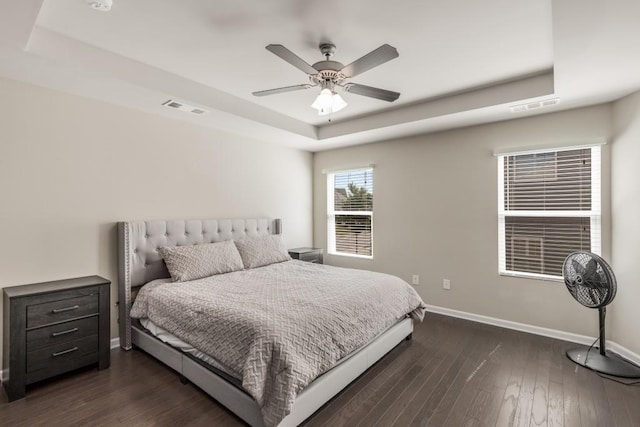 bedroom featuring a raised ceiling, ceiling fan, and dark wood-type flooring