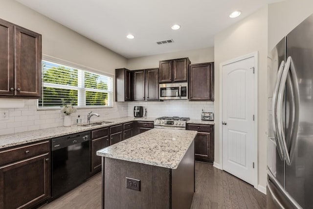 kitchen with appliances with stainless steel finishes, dark hardwood / wood-style flooring, dark brown cabinets, sink, and a kitchen island