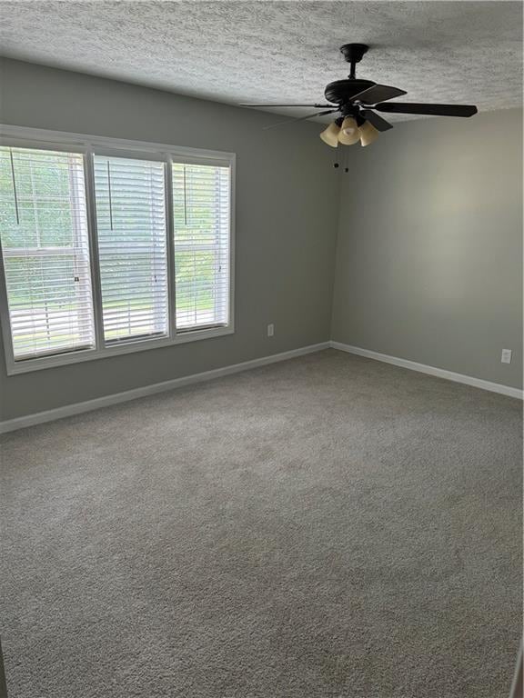 carpeted empty room with ceiling fan and a textured ceiling