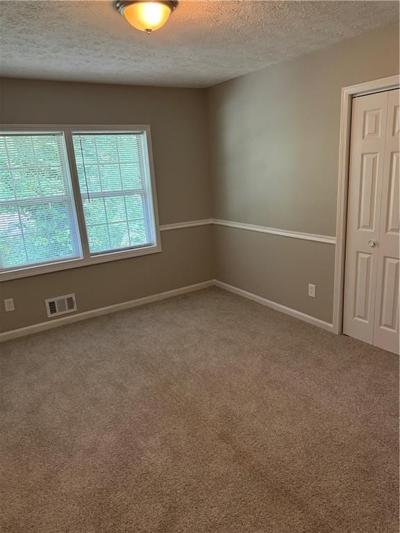 unfurnished room featuring carpet and a textured ceiling