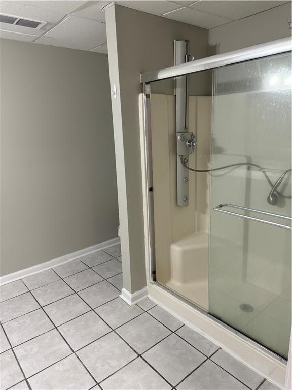 bathroom with a paneled ceiling, tile patterned floors, and a shower with door