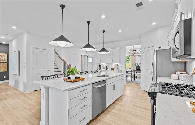 352 Foxglove Way, Mcdonough, GA 30253 - kitchen featuring appliances with stainless steel finishes, a sink, white cabinets, a center island with sink, and light wood-style flooring