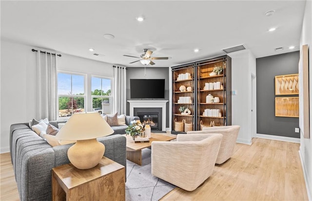 352 Foxglove Way, Mcdonough, GA 30253 - living room with light wood-style flooring, a ceiling fan, a glass covered fireplace, recessed lighting, and baseboards