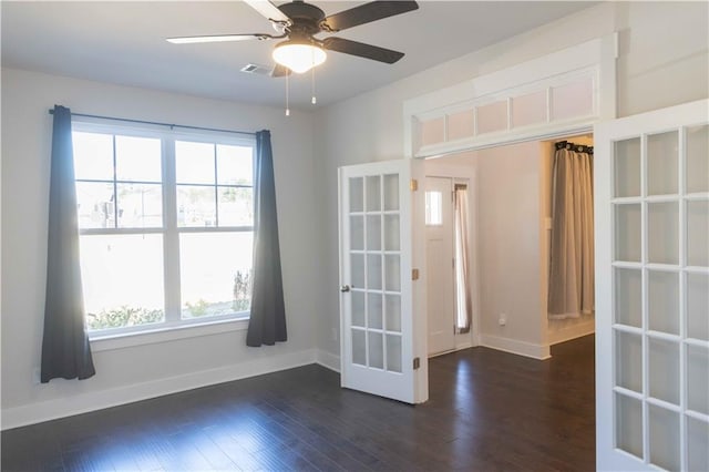 empty room with a healthy amount of sunlight, ceiling fan, and dark hardwood / wood-style floors