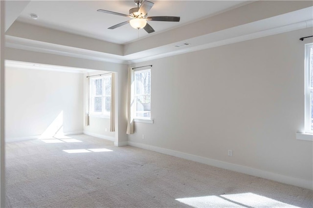 unfurnished room with a tray ceiling, light carpet, and ceiling fan