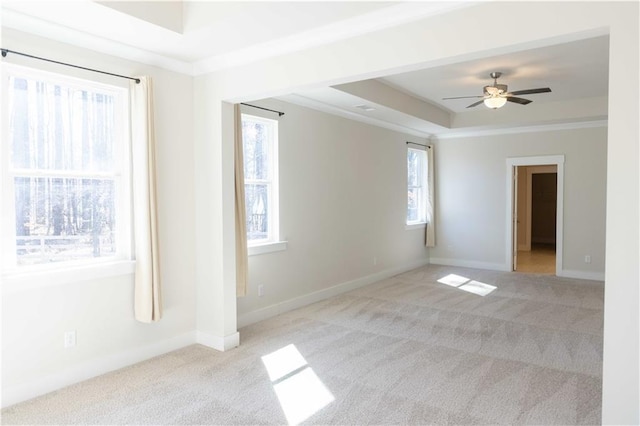 empty room featuring ceiling fan, crown molding, a raised ceiling, and light carpet