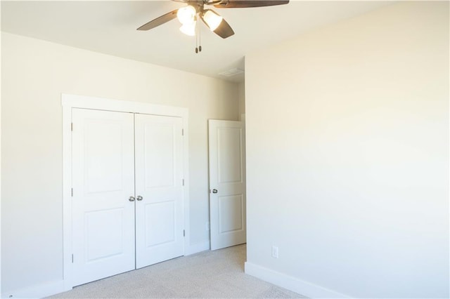 unfurnished bedroom featuring ceiling fan, light carpet, and a closet