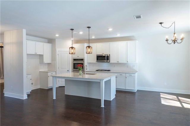 kitchen featuring a center island with sink, white cabinetry, and decorative light fixtures