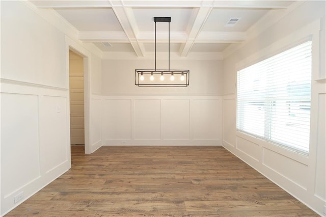 unfurnished dining area featuring beam ceiling, a decorative wall, wood finished floors, and coffered ceiling