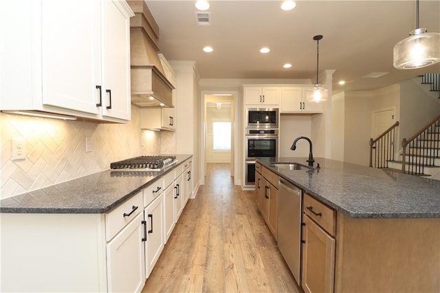 kitchen featuring visible vents, a sink, white cabinetry, stainless steel appliances, and light wood-style floors