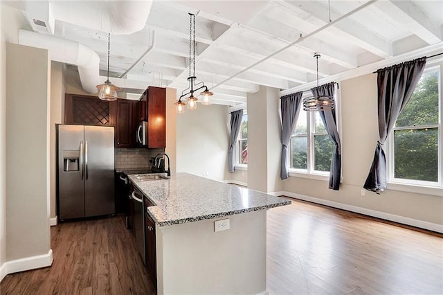 kitchen featuring appliances with stainless steel finishes, sink, decorative backsplash, hardwood / wood-style flooring, and light stone counters