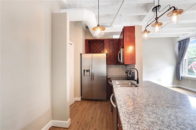 kitchen with sink, appliances with stainless steel finishes, tasteful backsplash, light hardwood / wood-style floors, and decorative light fixtures