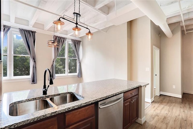 kitchen featuring light stone countertops, sink, stainless steel dishwasher, and decorative light fixtures