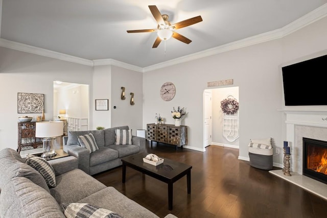 living room featuring ornamental molding, dark wood-style flooring, baseboards, ceiling fan, and a premium fireplace