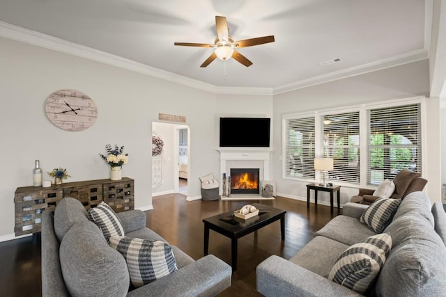 living area featuring ceiling fan, a lit fireplace, ornamental molding, and visible vents