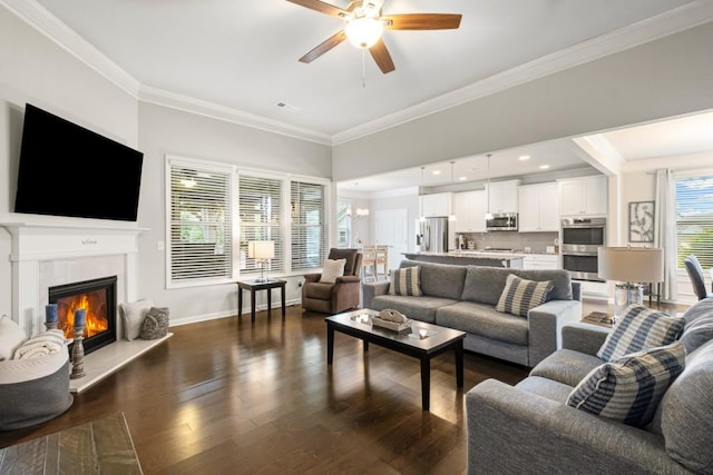 living area featuring ceiling fan, ornamental molding, baseboards, and dark wood-type flooring