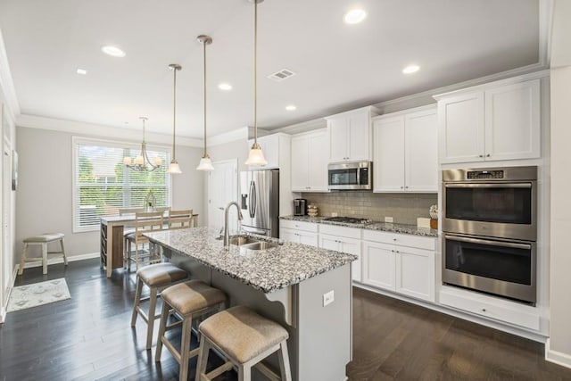 kitchen with visible vents, crown molding, a center island with sink, a sink, and stainless steel appliances