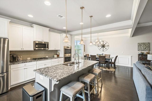 kitchen featuring visible vents, ornamental molding, a sink, appliances with stainless steel finishes, and backsplash