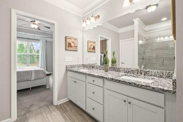 ensuite bathroom with crown molding, a ceiling fan, baseboards, a shower stall, and a sink