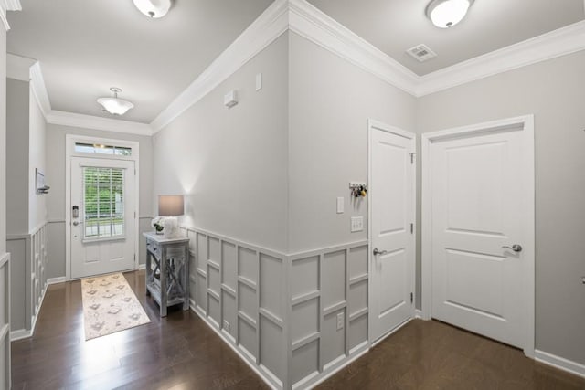foyer entrance featuring dark wood-style flooring, visible vents, crown molding, wainscoting, and a decorative wall
