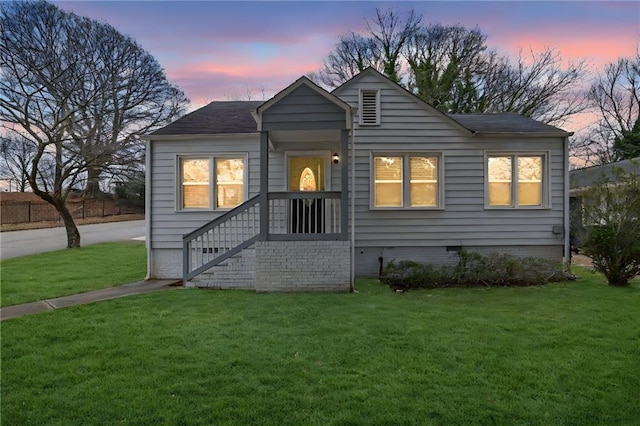 back house at dusk with a lawn