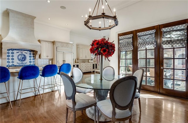 dining area with a chandelier, hardwood / wood-style flooring, french doors, and crown molding