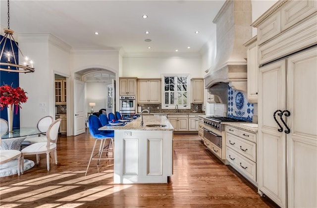 kitchen with sink, custom exhaust hood, a center island with sink, and hardwood / wood-style floors