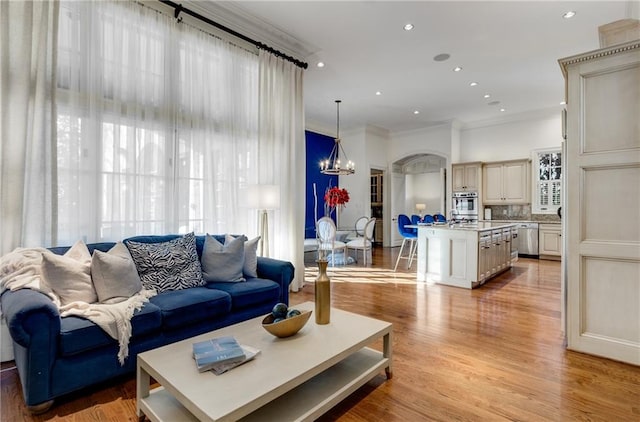 living room with light hardwood / wood-style floors, ornamental molding, and a notable chandelier