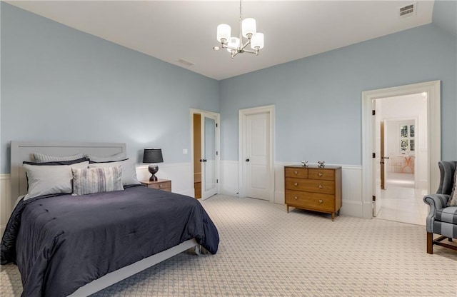 bedroom featuring an inviting chandelier, light colored carpet, and ensuite bath