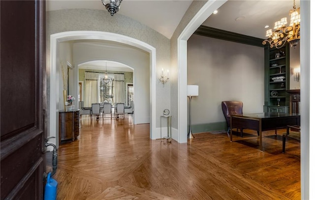 interior space with an inviting chandelier, built in features, parquet flooring, and ornamental molding