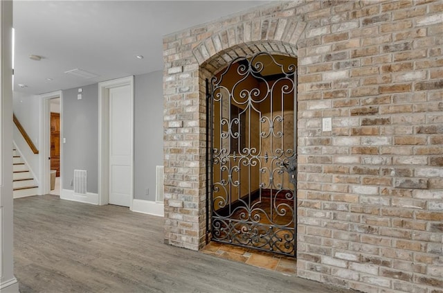 interior space featuring brick wall and wood-type flooring