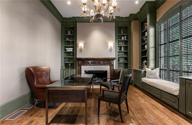 living area with hardwood / wood-style flooring, ornamental molding, built in shelves, and an inviting chandelier