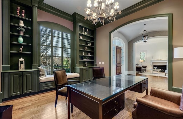 office space featuring plenty of natural light, light hardwood / wood-style flooring, built in shelves, and a chandelier