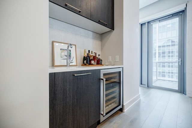 bar with light wood finished floors, a bar, wine cooler, and plenty of natural light