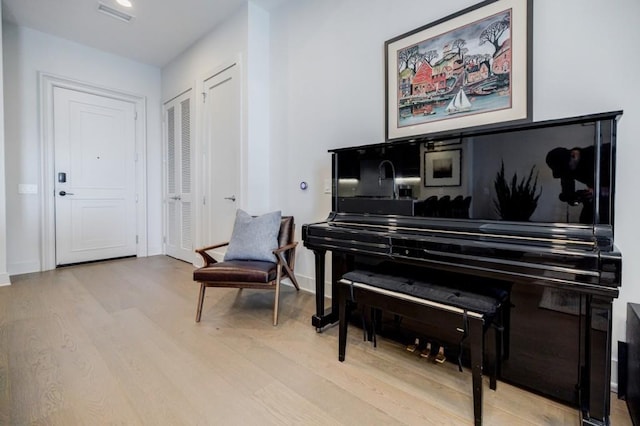 living area featuring baseboards, visible vents, and wood finished floors