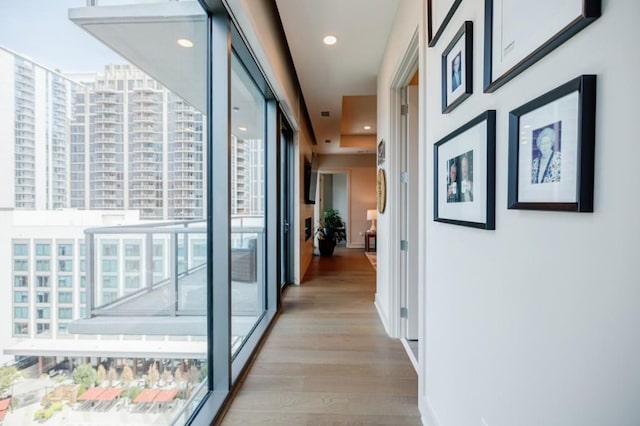 corridor with baseboards, recessed lighting, and light wood-style floors