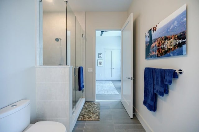 bathroom with a stall shower, tile patterned flooring, toilet, and baseboards