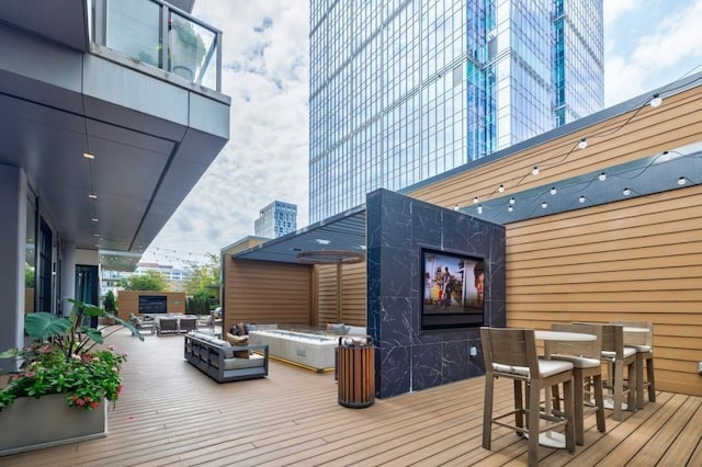 wooden deck with outdoor dining area, a jacuzzi, and an outdoor living space