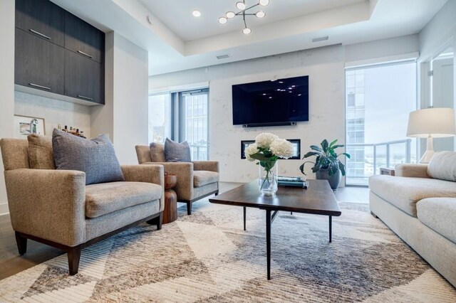 interior space featuring light wood-style floors, a high end fireplace, a raised ceiling, and visible vents