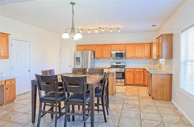 kitchen with decorative light fixtures, backsplash, stainless steel appliances, and sink