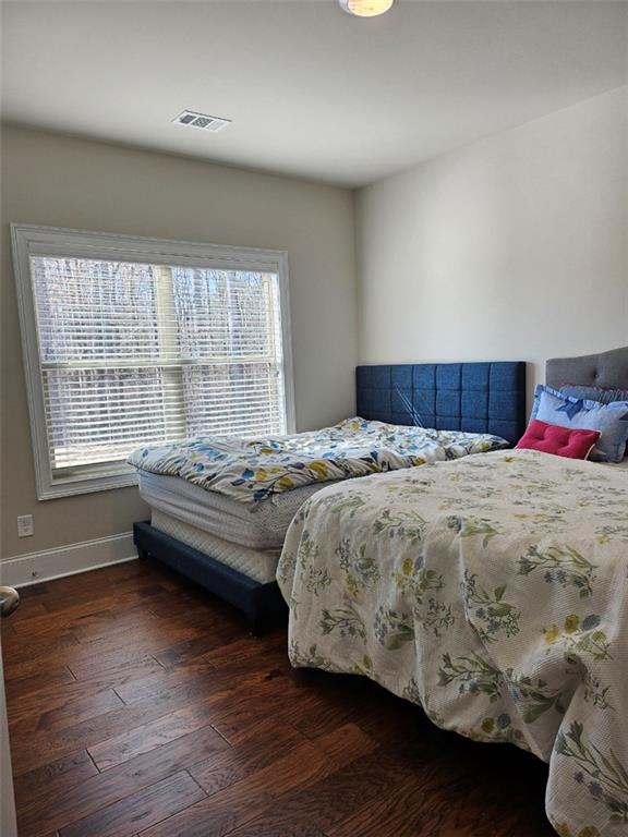 bedroom with wood finished floors, visible vents, and baseboards