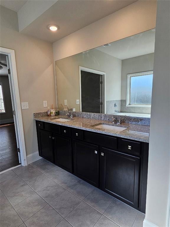 full bathroom featuring double vanity, baseboards, tile patterned floors, and a sink