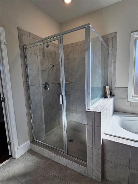 full bathroom with tile patterned flooring, a shower stall, and a garden tub