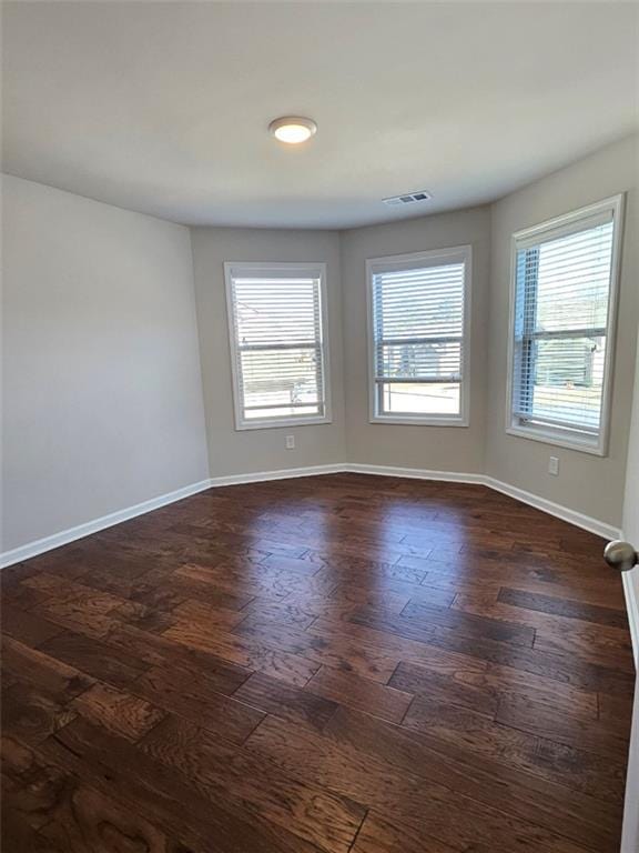 spare room with dark wood finished floors, baseboards, and visible vents