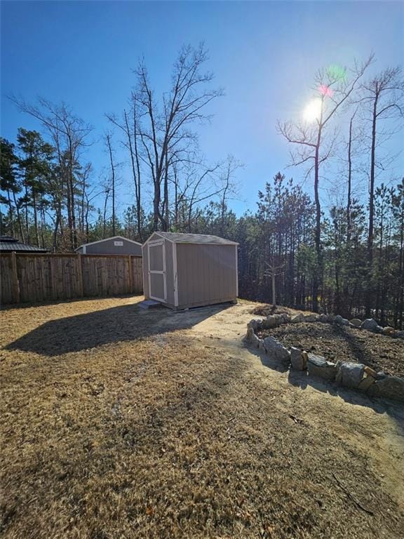 view of yard with a shed, an outdoor structure, and fence