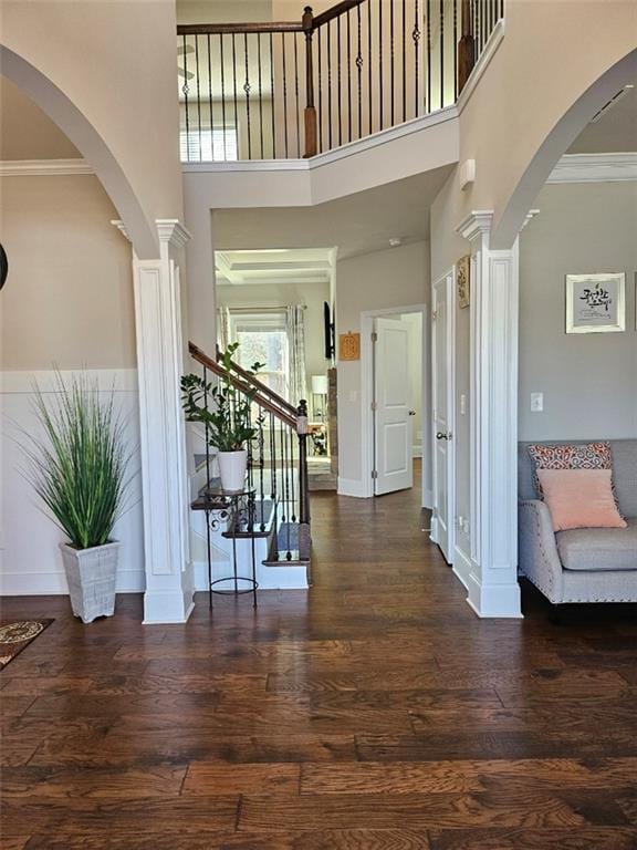 entryway with ornamental molding, baseboards, ornate columns, and wood finished floors