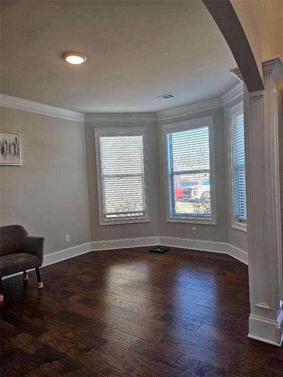 unfurnished room with dark wood-style floors, visible vents, crown molding, and baseboards